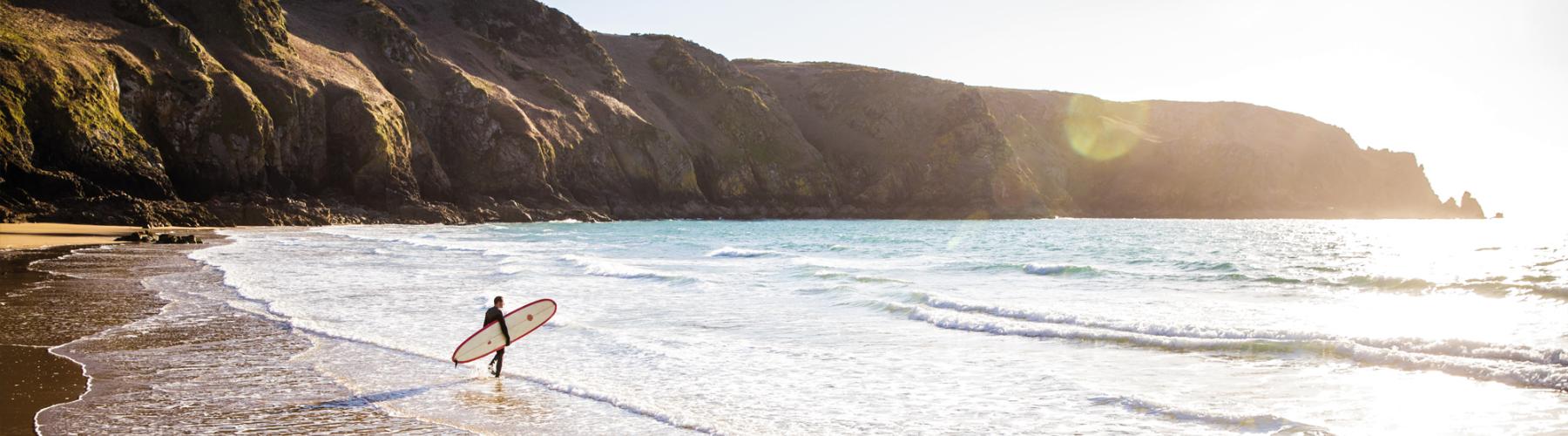 A surfer holding his board and walking towards the shoreline